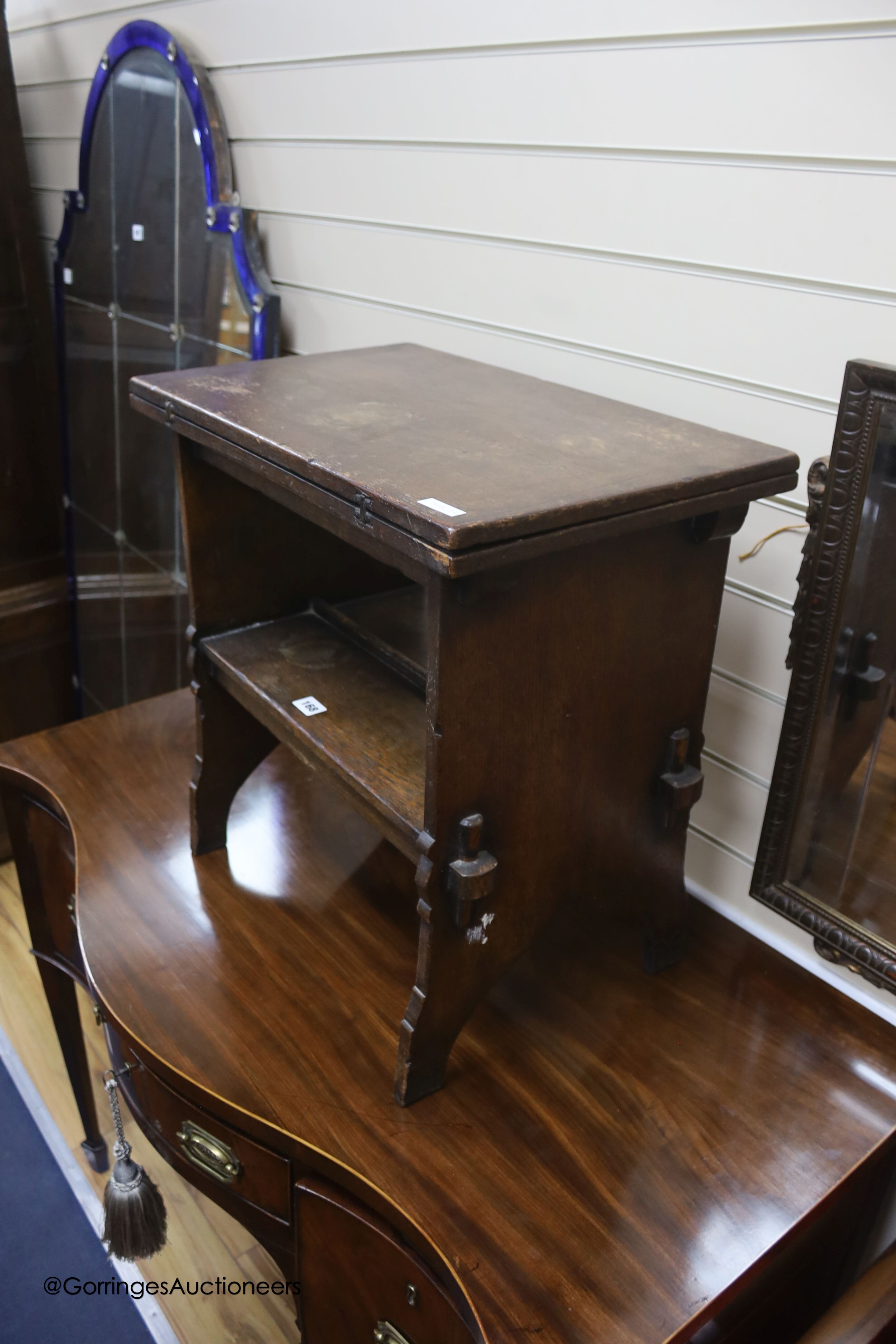 An early 20th century solid, dark oak occasional table with folding top and undertier